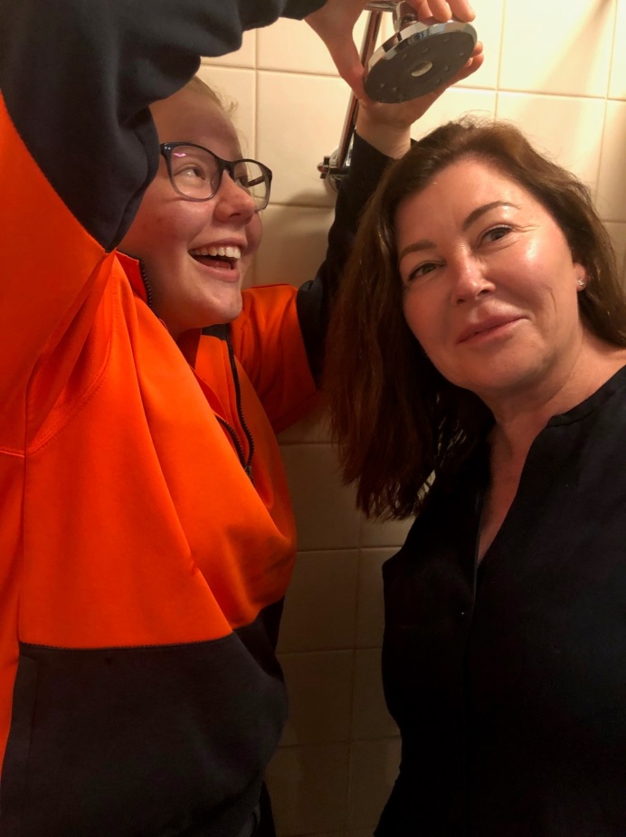 Denmark Agricultural College student Jane Thompson prepares to demonstrate the newly installed showerheads to Residential Manager Kelli Gillies.
